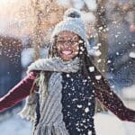Woman celebrates finding the best treatment for seasonal affective disorder by throwing snow in the air