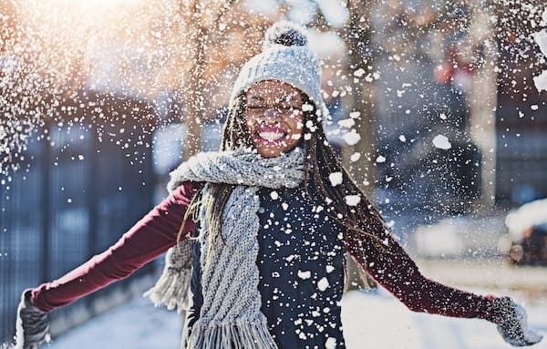 Woman celebrates finding the best treatment for seasonal affective disorder by throwing snow in the air