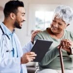A young doctor sharing information about symptoms of Depression in older adults from his digital tablet with an older patient