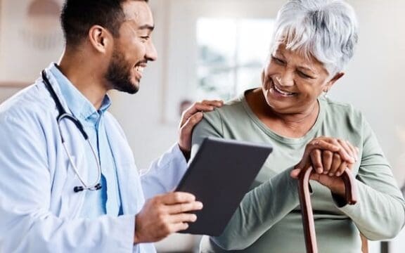 A young doctor sharing information about symptoms of Depression in older adults from his digital tablet with an older patient