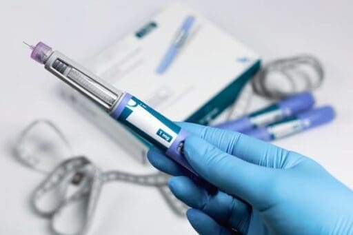 Hands in blue surgical gloves holding Ozempic Insulin injection pen, usually for diabetics but new research suggests we may use Ozempic for mental health