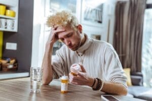 A person sitting and holding their head in their hands while looking at the pill bottles, unsure what to do when antidepressants stop working