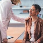 Patient sitting in a doctor's office smiling as the physician explains tms coil placement