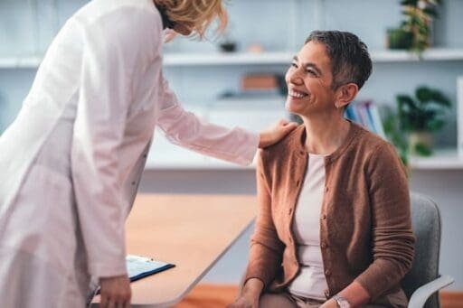 Patient sitting in a doctor's office smiling as the physician explains tms coil placement