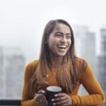 smiling patient holds coffee mug after TMS treatment alleviates her irritability in Depression