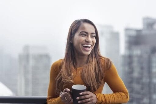 smiling patient holds coffee mug after TMS treatment alleviates her irritability in Depression