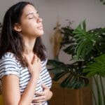 A person closing their eyes and smiling, with hands on their chest in comfort, after finding Depression relief with TMS