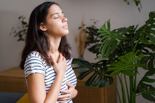 A person closing their eyes and smiling, with hands on their chest in comfort, after finding Depression relief with TMS
